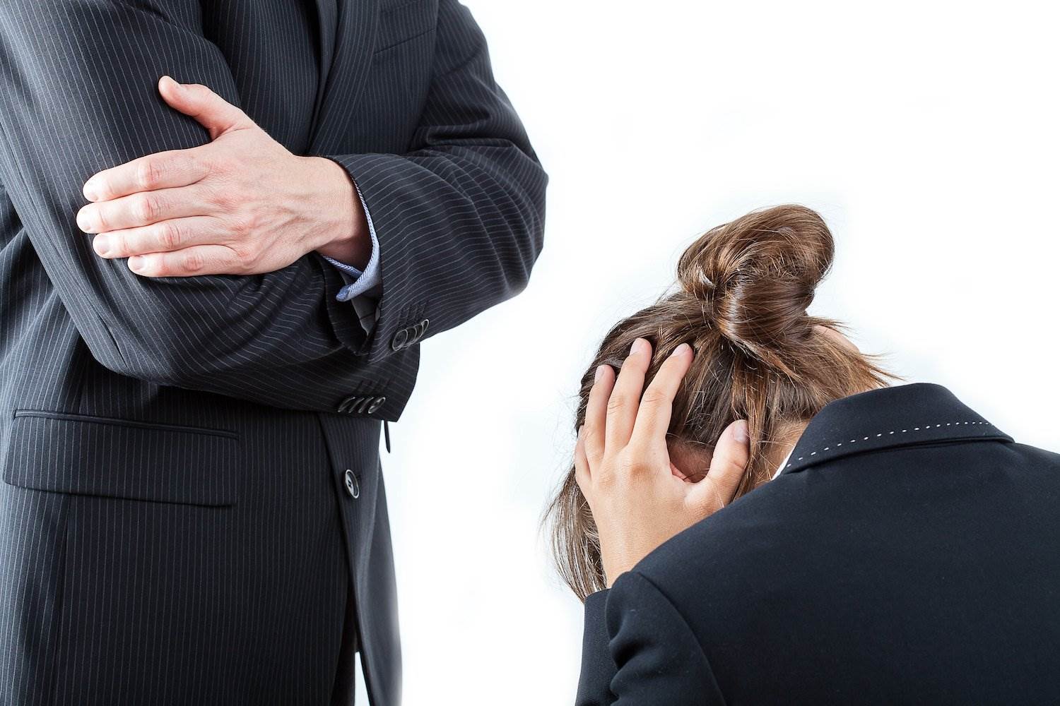 Seated woman office worker being scolded by male boss standing over her as an example of workplace bullying, against a white background
