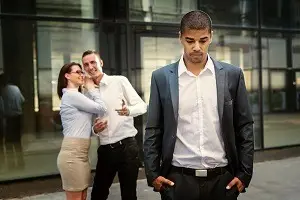 White employees laughing behind back of black-employee representing racial harassment