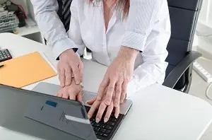 Man with hands on female coworkers hands on keyboard