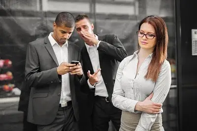 Two men whispering about female colleague