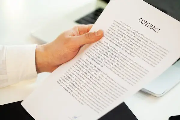 close-up of hand holding a paper that says contract, which includes a provision on comp time