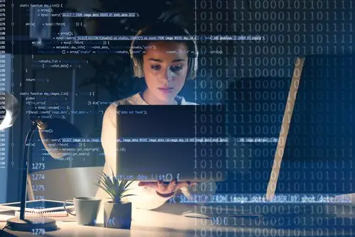 female computer programmer working late in front of her computer in her office, and the image is overlaid in images of binary code