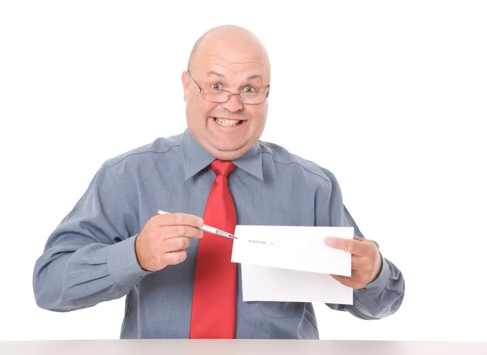 A smirking manager in a grey shirt and red tie holding an employment agreement in one hand and a pen in the other, against a white background