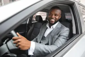 Happy man in business suit driving his sedan during a work trip
