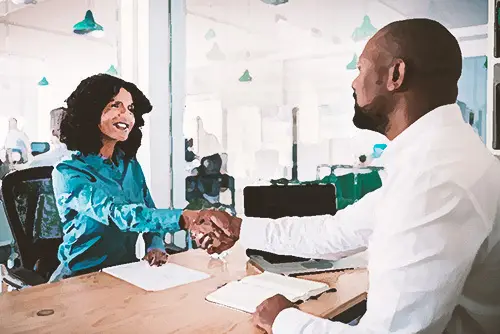 Employer shaking hands with an employee over the employer's work desk