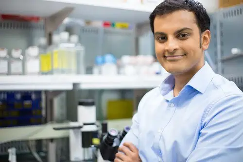 Indian lab technician in his lab near a microscope