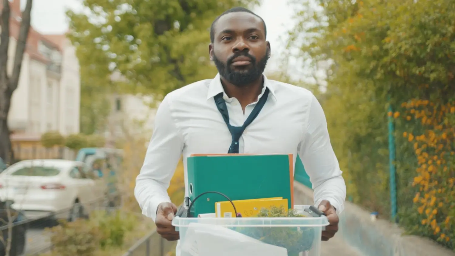 Recently laid off worker leaving office with belongings in a plastic case