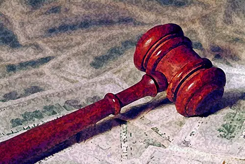 judge's wooden gavel lying on top of dollar bills