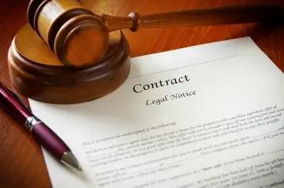 Employment contract on a wooden table along with a gavel and ball-point pen