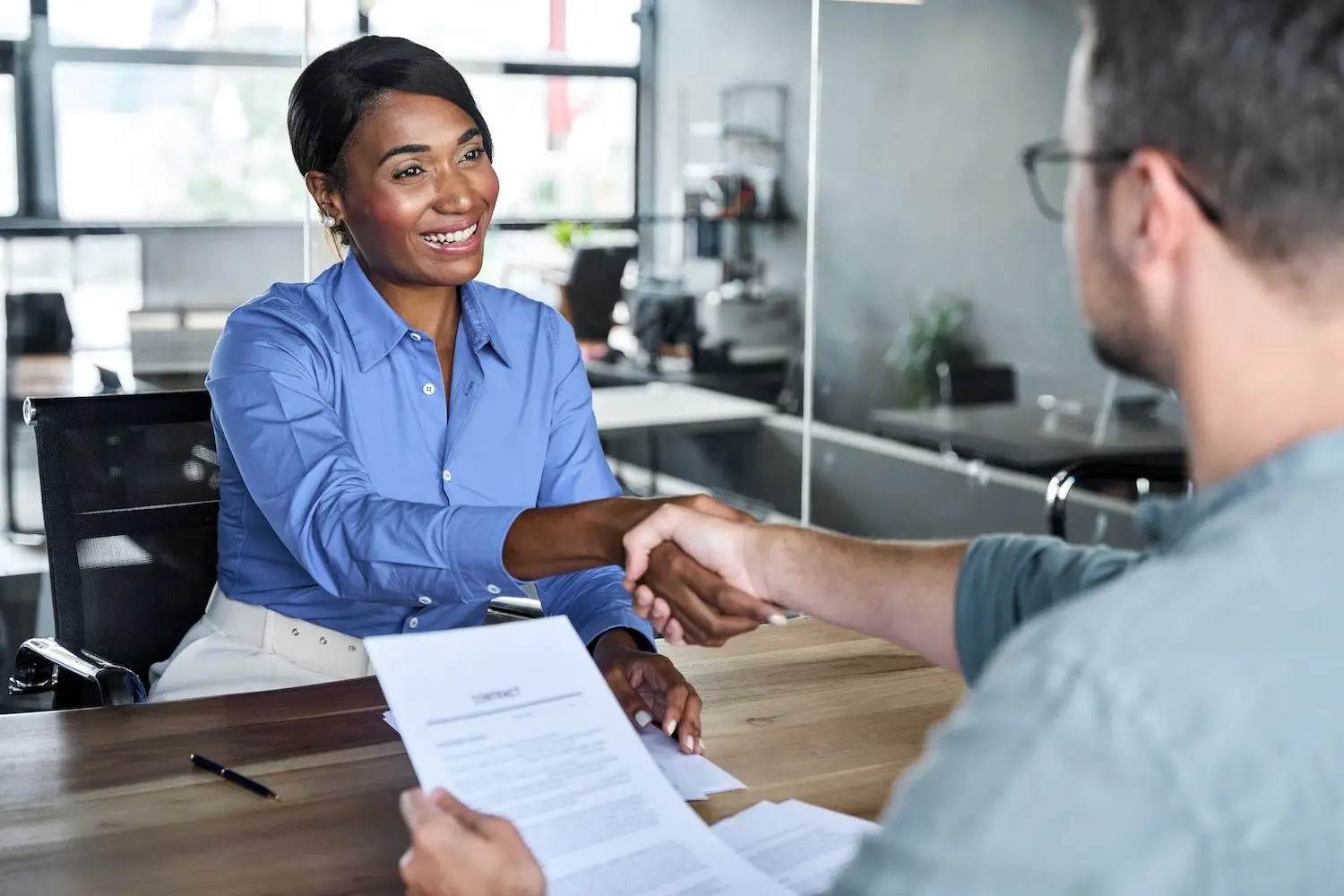 Smiling job applicant shaking hands with her interviewer