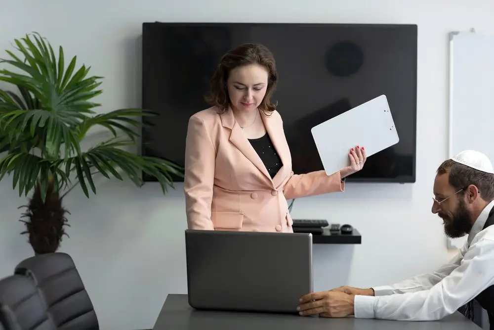 A man wearing a yarmulke in an office with a woman during a meeting.