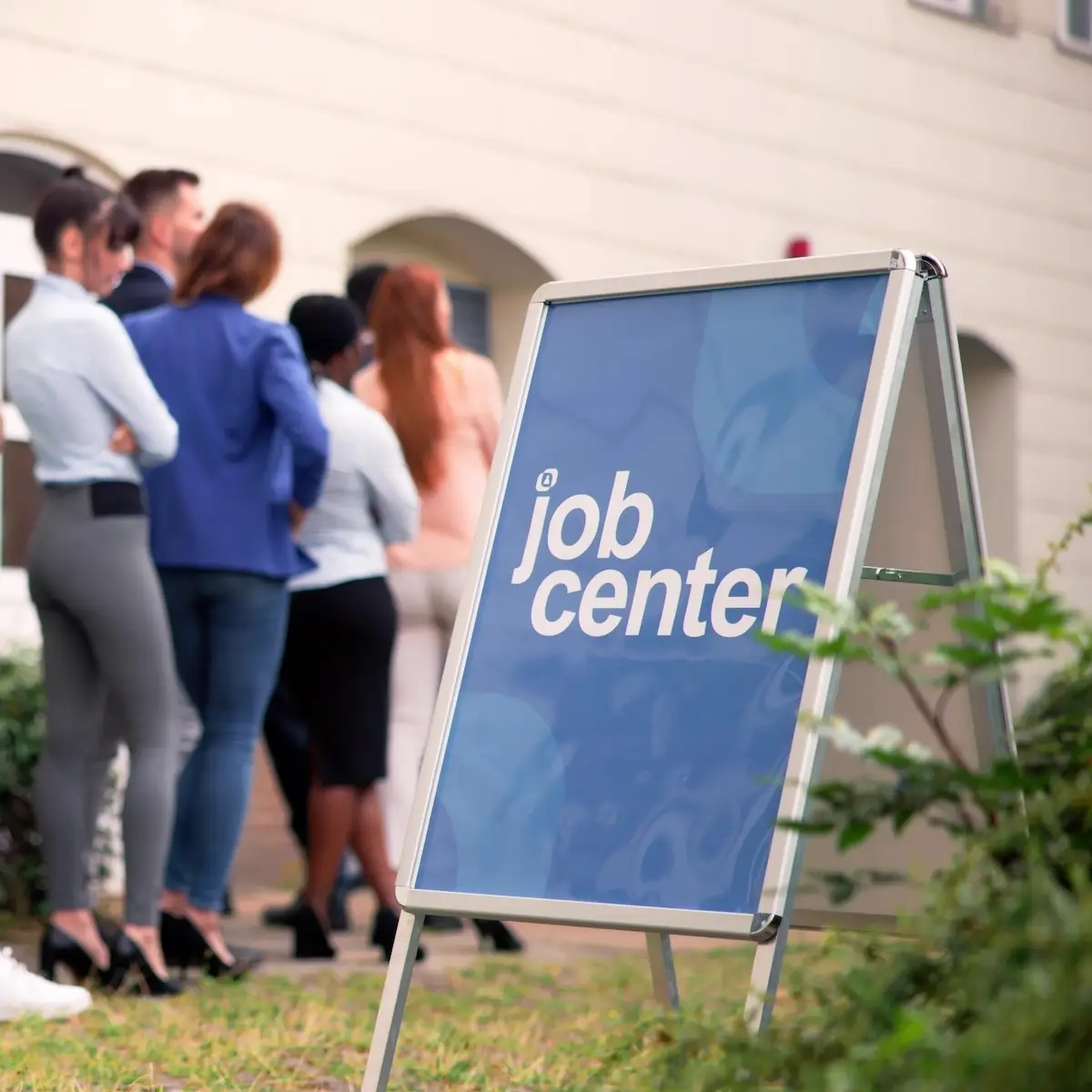 Line of job seekers waiting to get into a job fair next to a sign that reads, "Job Center."