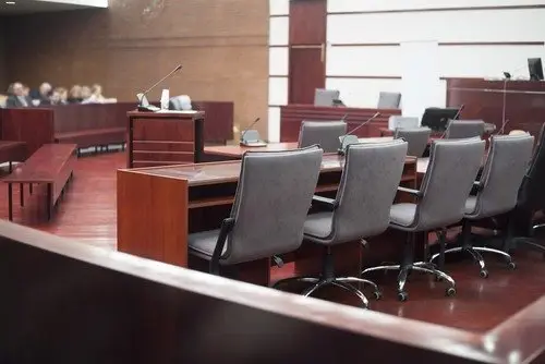 Large wooden courtroom with empty chairs during a recess