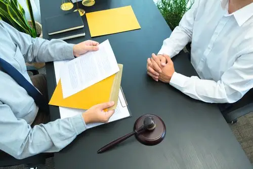Misclassified worker speaking with an employment law attorney at his desk, and the attorney has legal documents and a gavel