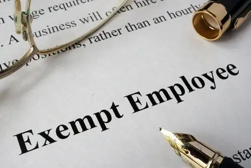 Document with "Exempt Employee" written on it along with a pen and glasses