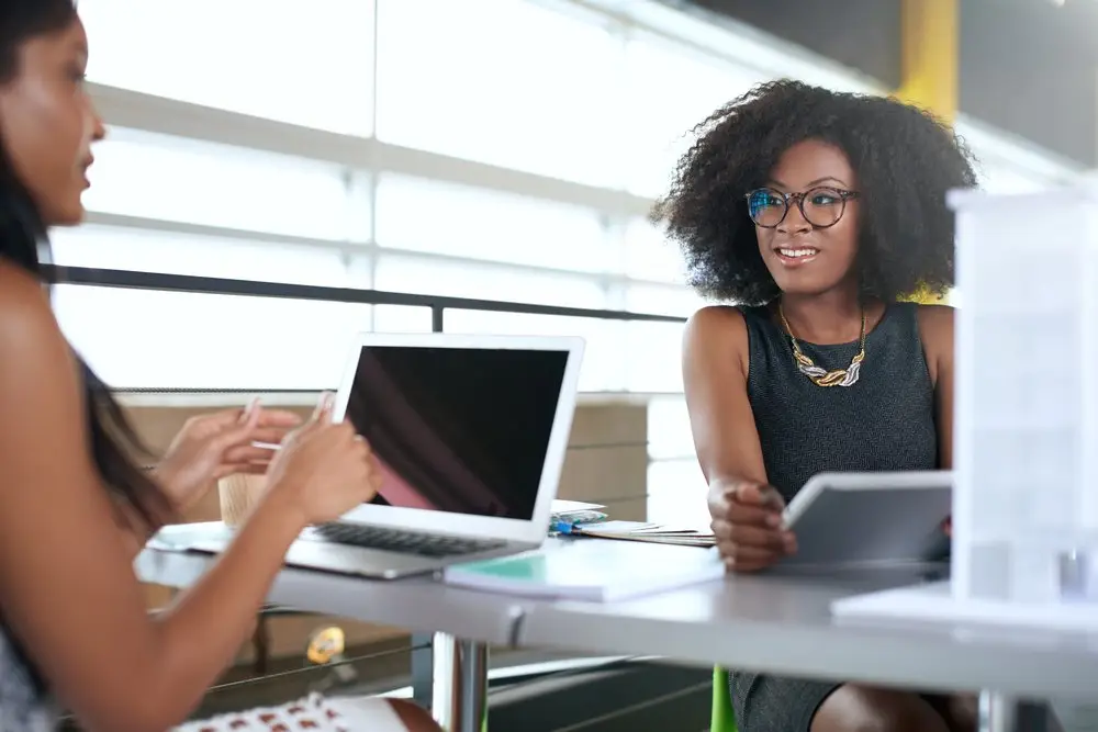 An African American boss and her African American employee at their office desks