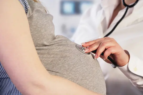 Doctor examining pregnant woman for qualifying disabilities for PDL. 
