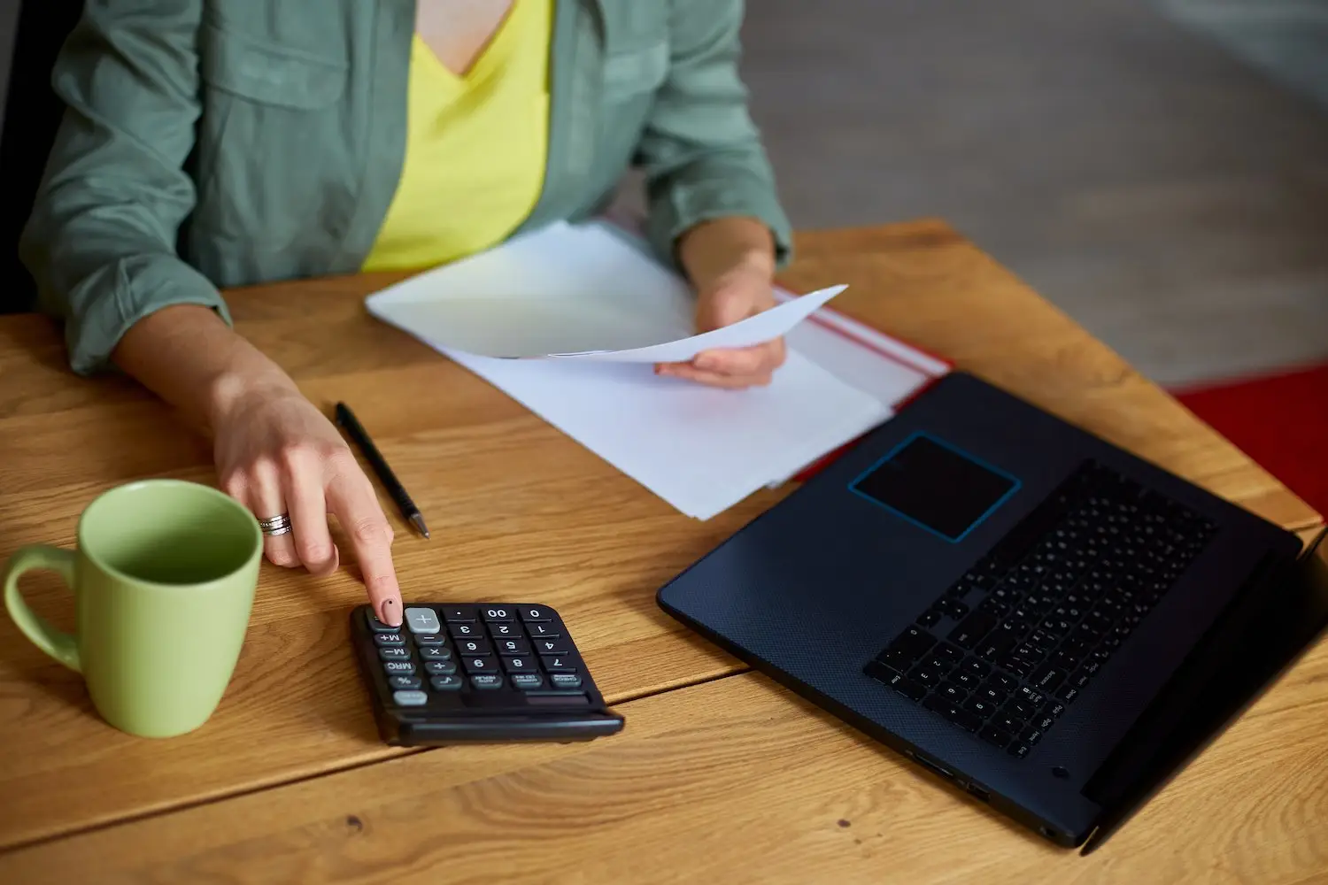 Woman employee at her desk using her calculator and her laptop to calculate her regular rate of pay