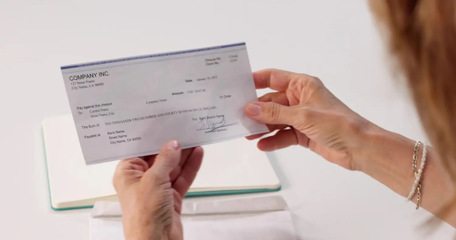 Woman employee holding her paycheck at her desk