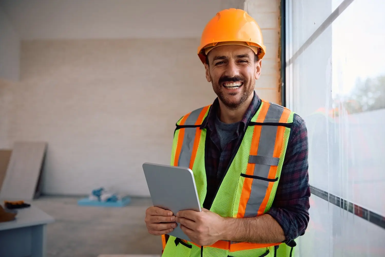 Smiling construction worker in hard hat holding a tablet