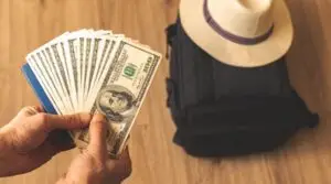 Travel cash next to a suitcase and a sun hat