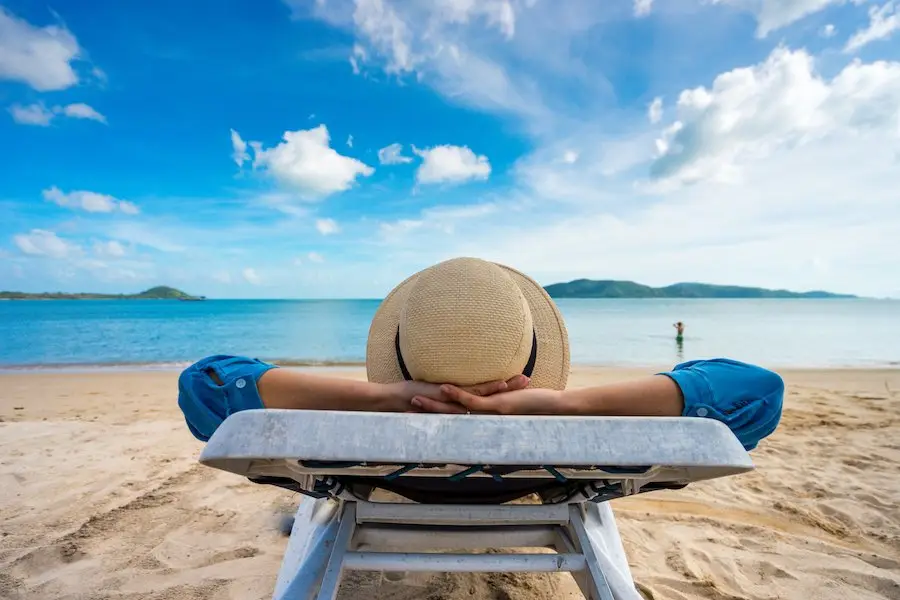 Person on lawn chair on beach during vacation