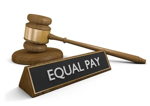 Wooden gavel behind a sign that says "equal pay" against a white background