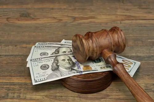 A wooden table holding a wooden gavel, and there is $400 in cash between the gavel and block