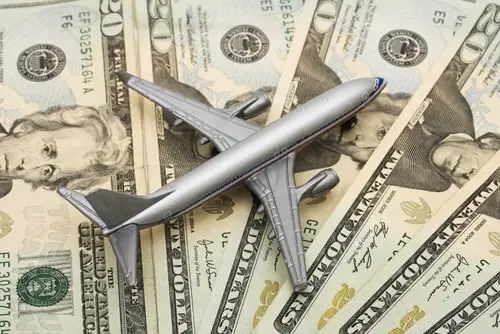 Model airplane sitting on spread of several $20 bills