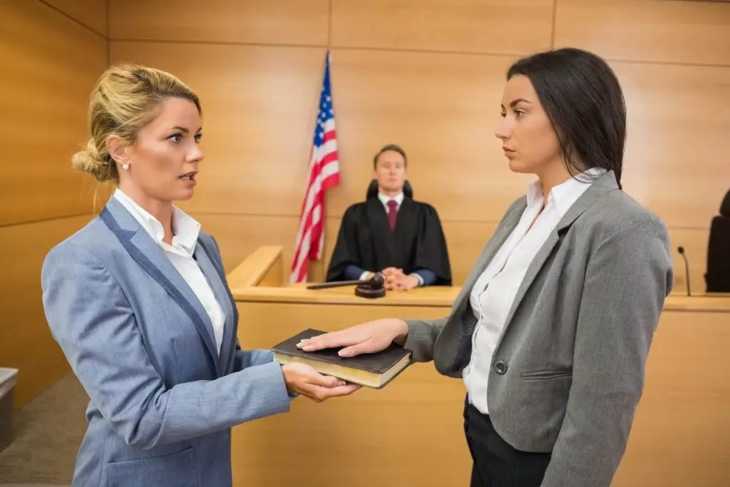 Crime victim being sworn in as a victim in court, and a judge is in the background watching next to an American flag