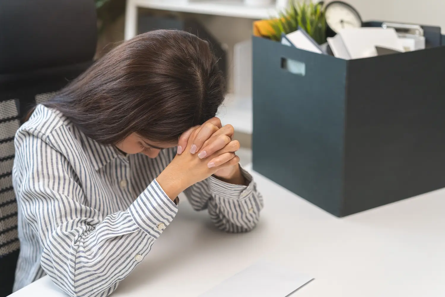 Sad employee holding her head in her hands at her work desk