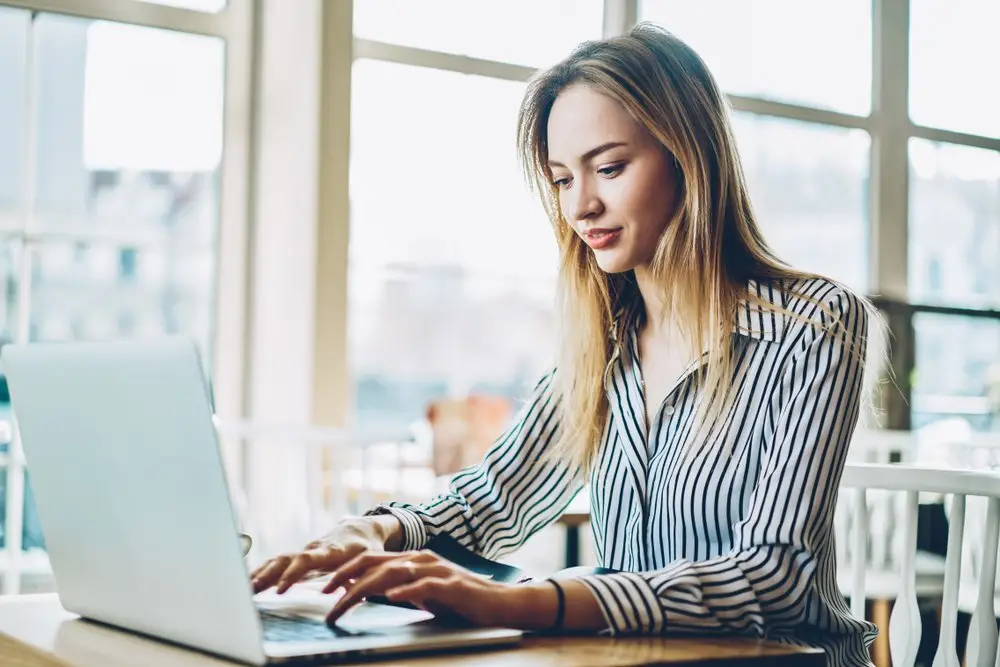 A young woman typing up a demand letter on her laptop.