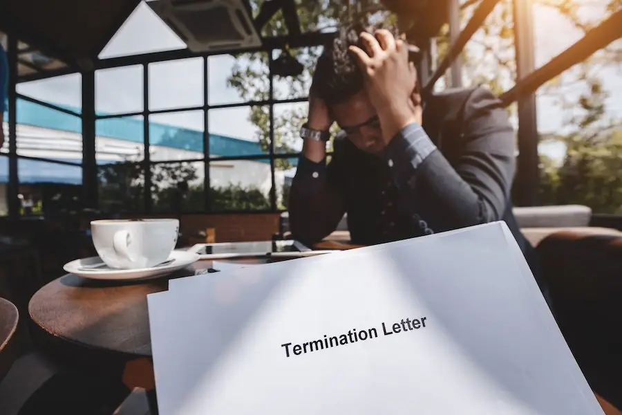 Distraught businessman holding his head in his hands after receiving a termination letter
